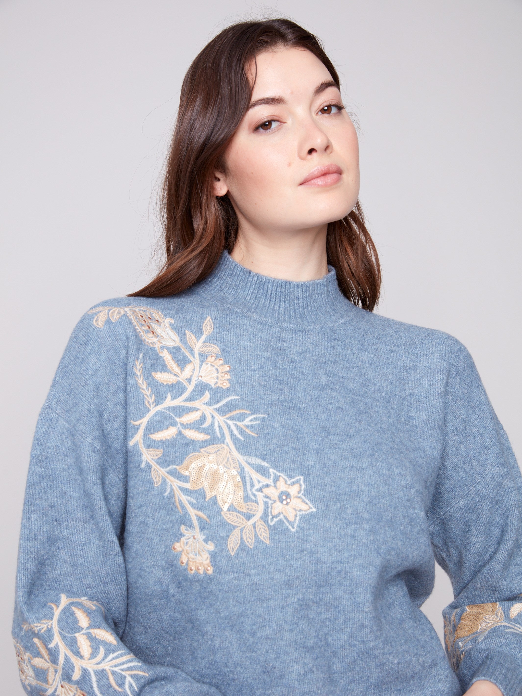 Chic denim sweater highlighted by its exquisite mock neck and detailed floral embroidery, adding a touch of elegance by Charlie B.