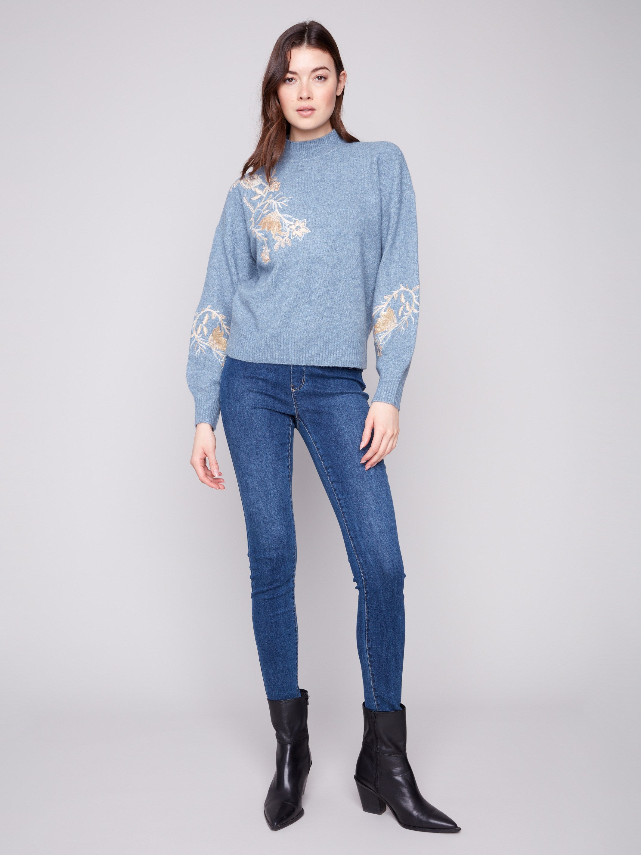 Stylish heather denim sweater with beautiful embroidered floral details and sequins, complemented by a classic mock neck by Charlie B.