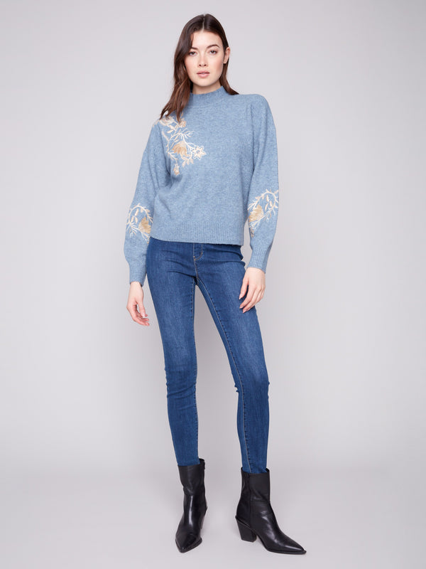 Stylish heather denim sweater with beautiful embroidered floral details and sequins, complemented by a classic mock neck by Charlie B.