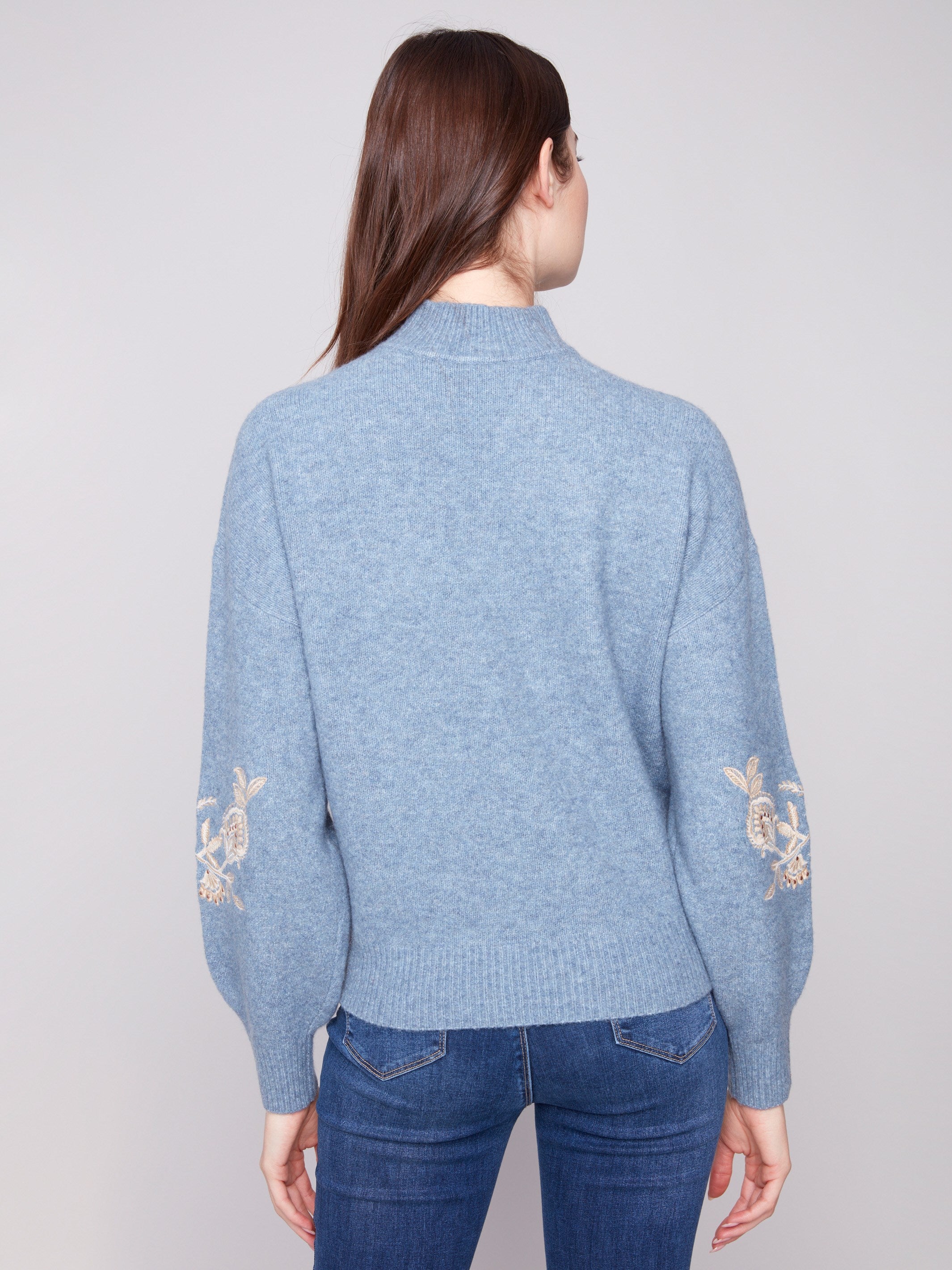 Heather denim sweater showcasing drop shoulders design with charming floral embroidery and subtle sequin accents by Charlie B.