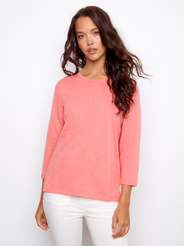 Soft pink top featuring a classic crew neckline, adding timeless style to any outfit. By Charlie B.