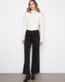 Black wide-leg pants in stretch twill fabric, paired with black boots and a white sweater by Charlie B.