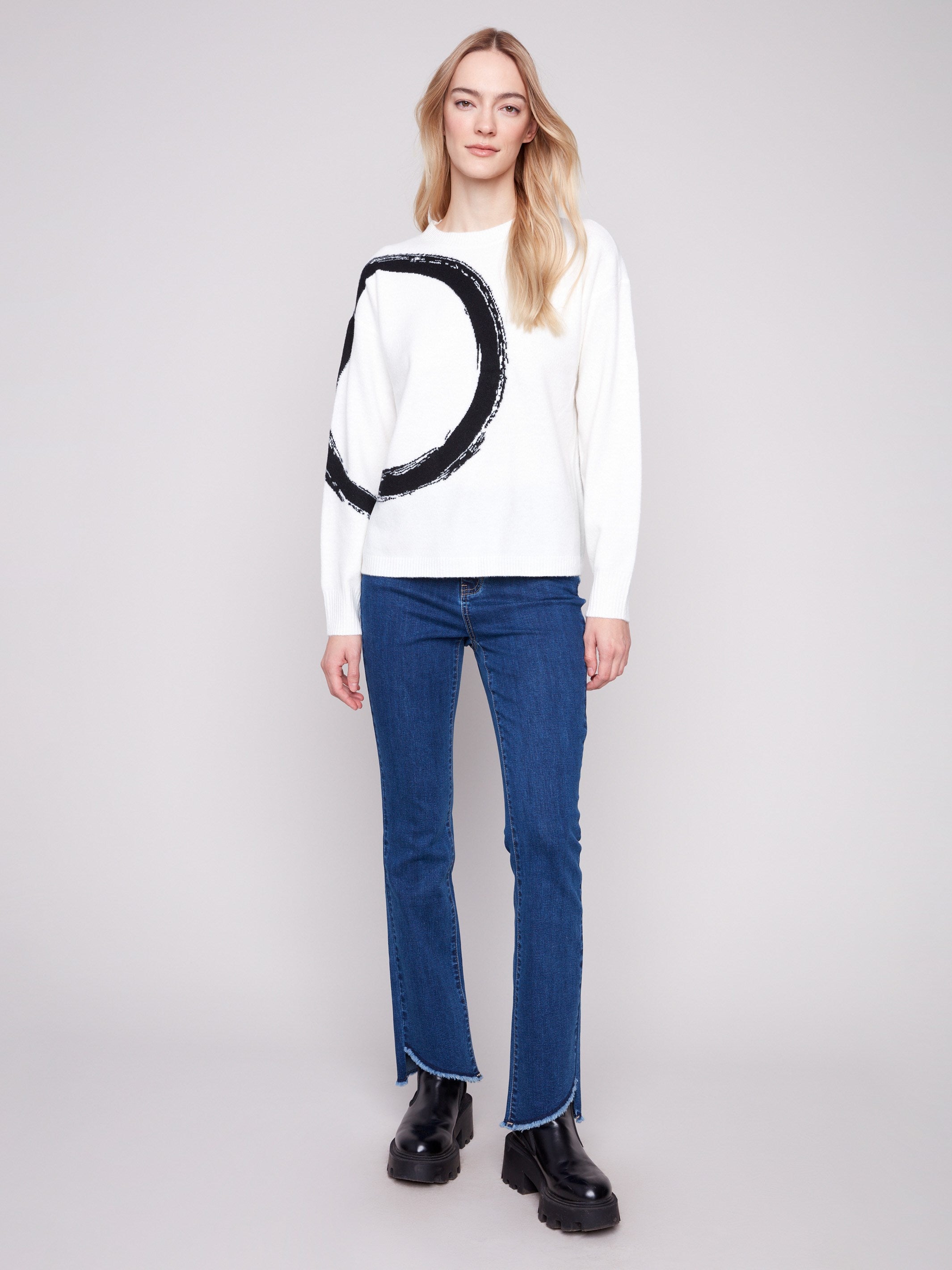 Featuring long sleeves, this ecru sweater boasts a striking black abstract circle design by Charlie B.