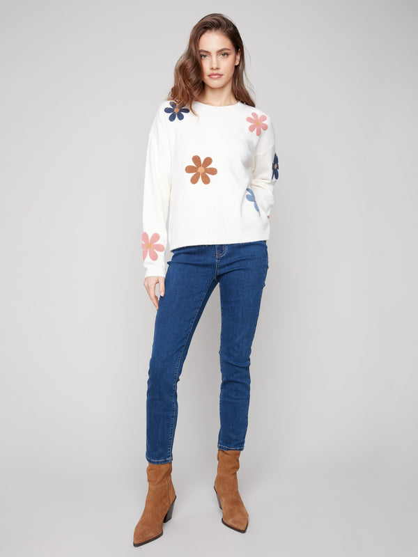 Ecru plush sweater showcasing drop shoulder design, adorned with colorful boucle flowers by Charlie B.