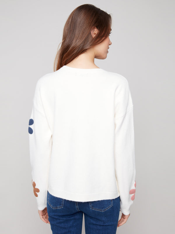Ecru plush sweater designed with cozy comfort in mind, highlighted by colorful boucle flower accents by Charlie B.