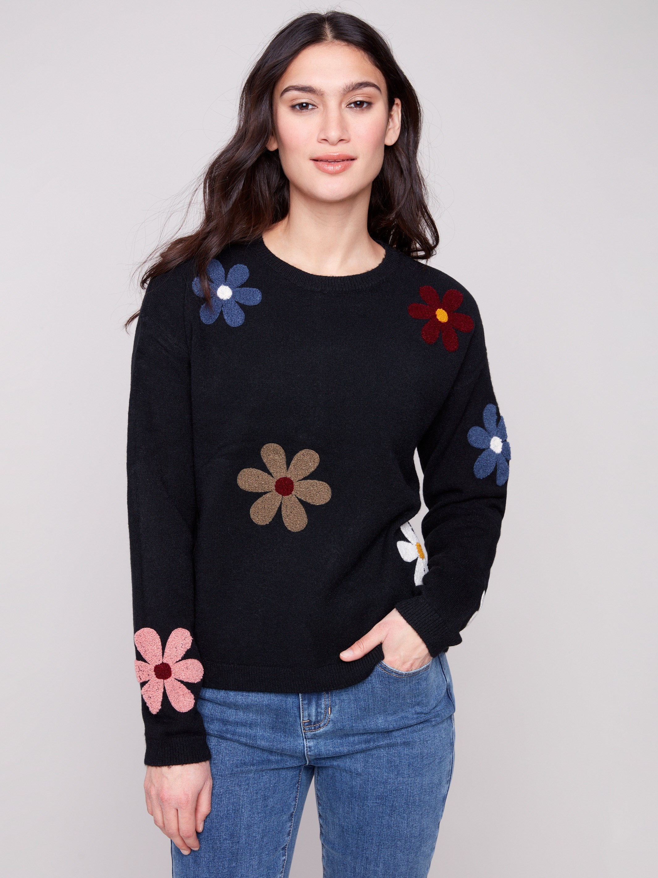 Black plush sweater with a classic crew neckline adorned with colorful boucle flower patches for a vibrant touch by Charlie B.