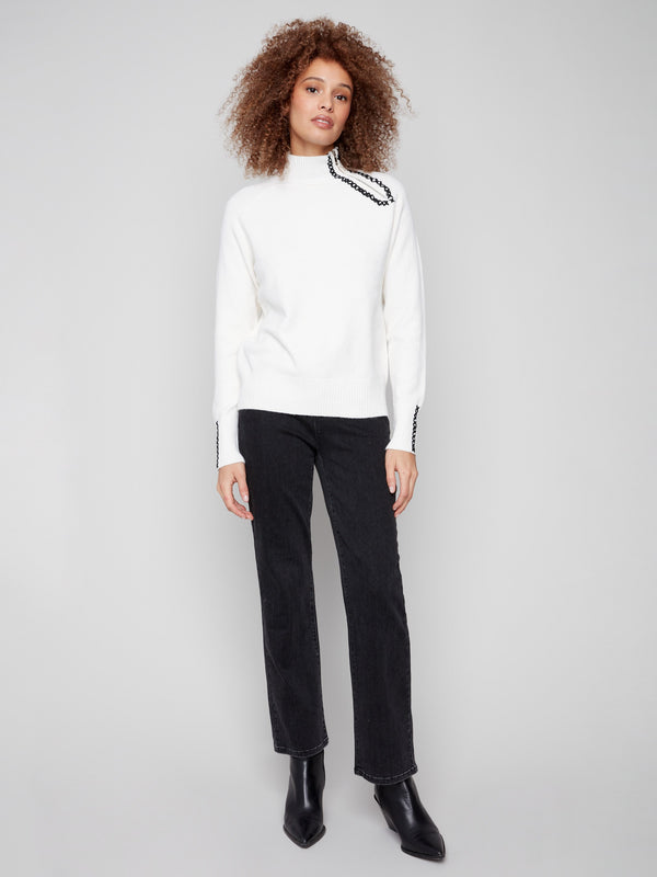 This ecru sweater showcases a unique zipper detail adding a modern touch to its classic design by Charlie B.
