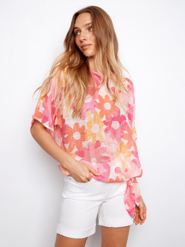 Blouse with vibrant floral design and side tie detail, showcasing the boat neckline by Charlie B.