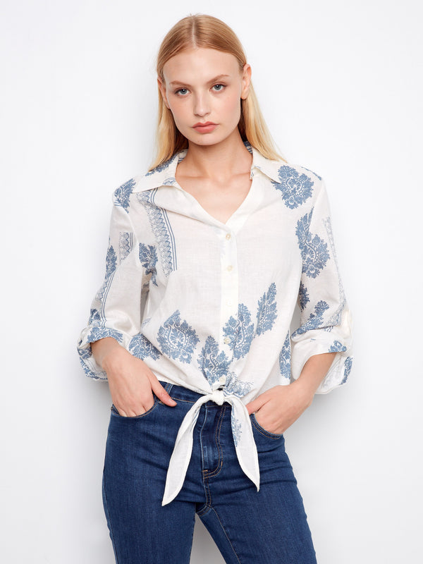Elegant blouse with a Johnny neckline, showcasing intricate blue patterns on white fabric. Finished by Charlie B.