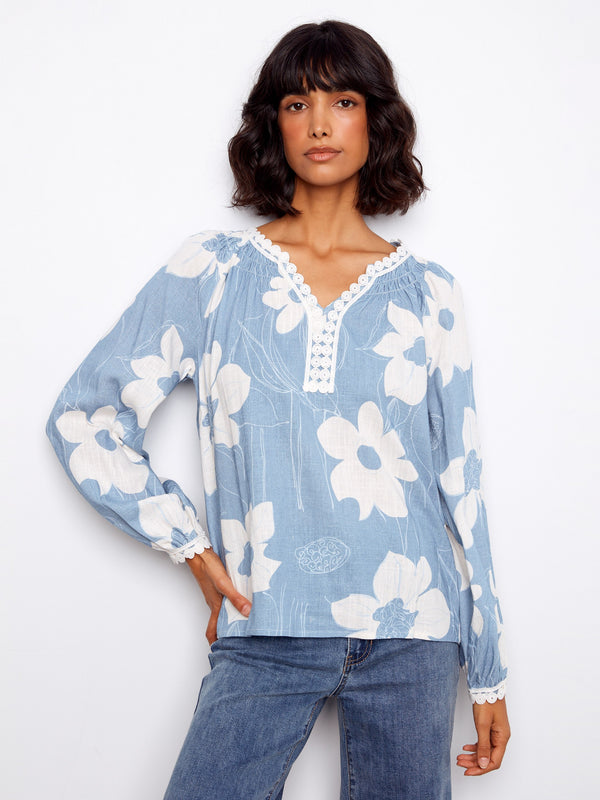 Floral blouse with a crochet trim neckline, featuring raglan sleeves and delicate detailing, perfect for casual elegance by Charlie B.