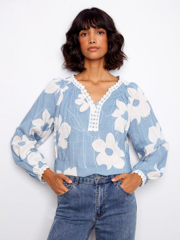 Stylish floral blouse highlighted by its unique notch neckline and intricate crochet details for added flair by Charlie B.