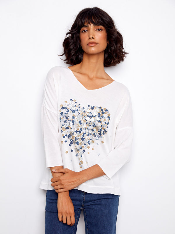 Elegant white top featuring a V-neck and heart-shaped floral placement print, ideal for any season by Charlie B.