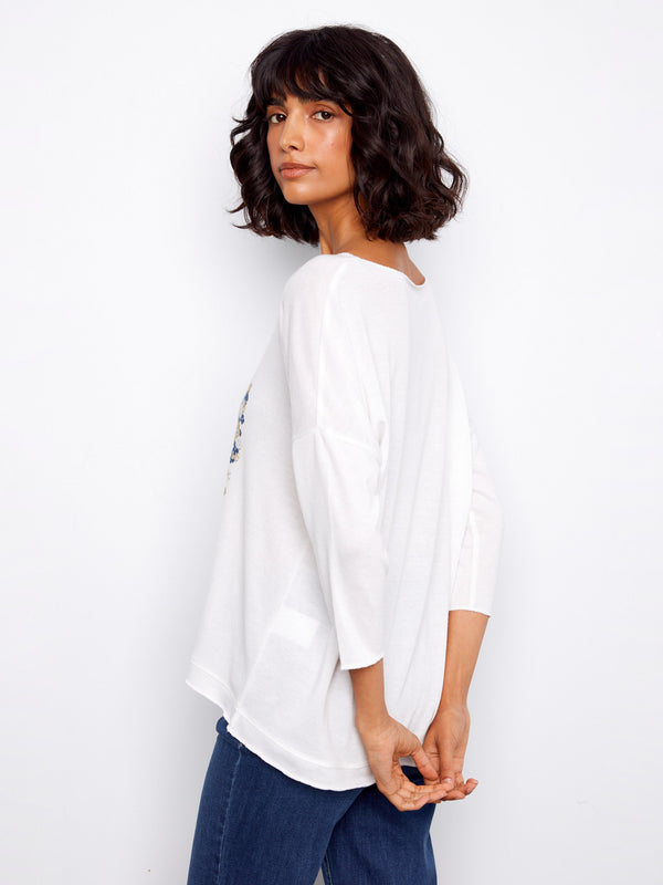 Versatile white V-neck top adorned with an eye-catching floral design, complete with 3/4 sleeves by Charlie B.