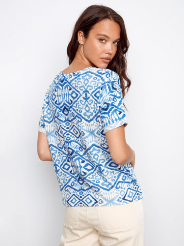 Elegant blue top highlighted by its unique pattern and V-neckline, ideal for versatile styling. Beige pants complete the look by Charlie B.