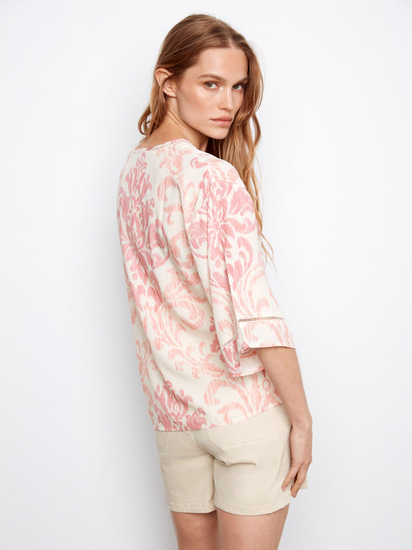 Abstract patterned blouse in pink and white, featuring wide elbow sleeves and button-front detail by Charlie B.