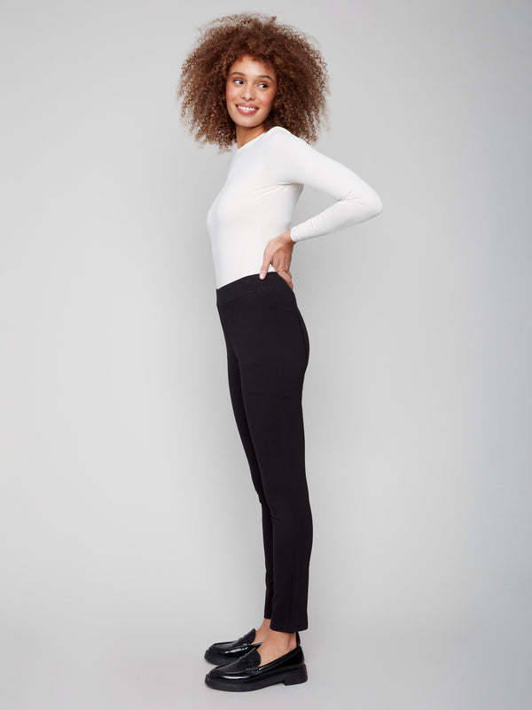Elegant black pull-on pants styled with a white top, emphasizing the slit detail at the hem by Charlie B.