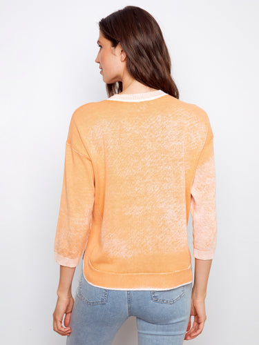 The unique reversed print adds an artistic touch to this soft orange top, enhancing its visual appeal. Designed by Charlie B.