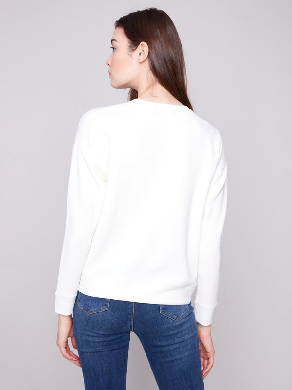 Ecru Scuba Knit Top enhanced with a classic crew neckline and delicate soutache accents to elevate your style by Charlie B.