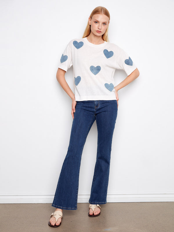 Stylish white sweater featuring a crew neckline and playful denim heart patches by Charlie B.