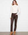 Woman styled in coffee-colored slim leg pants featuring a regular rise, paired with a white top and ankle boots by Charlie B.