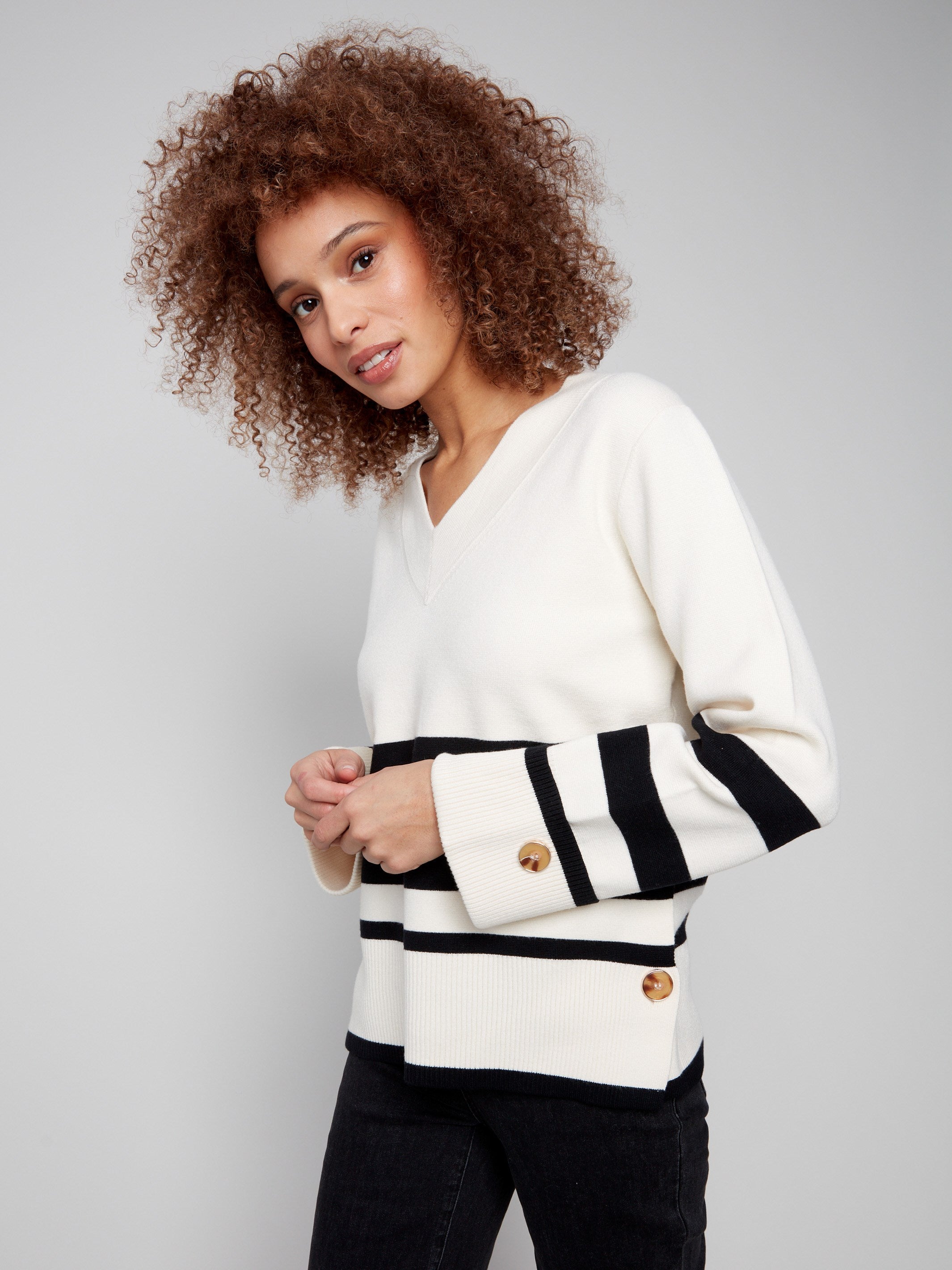 Elegant ecru striped sweater showcasing button details on the sleeves, complemented by wide cuffs by Charlie B.