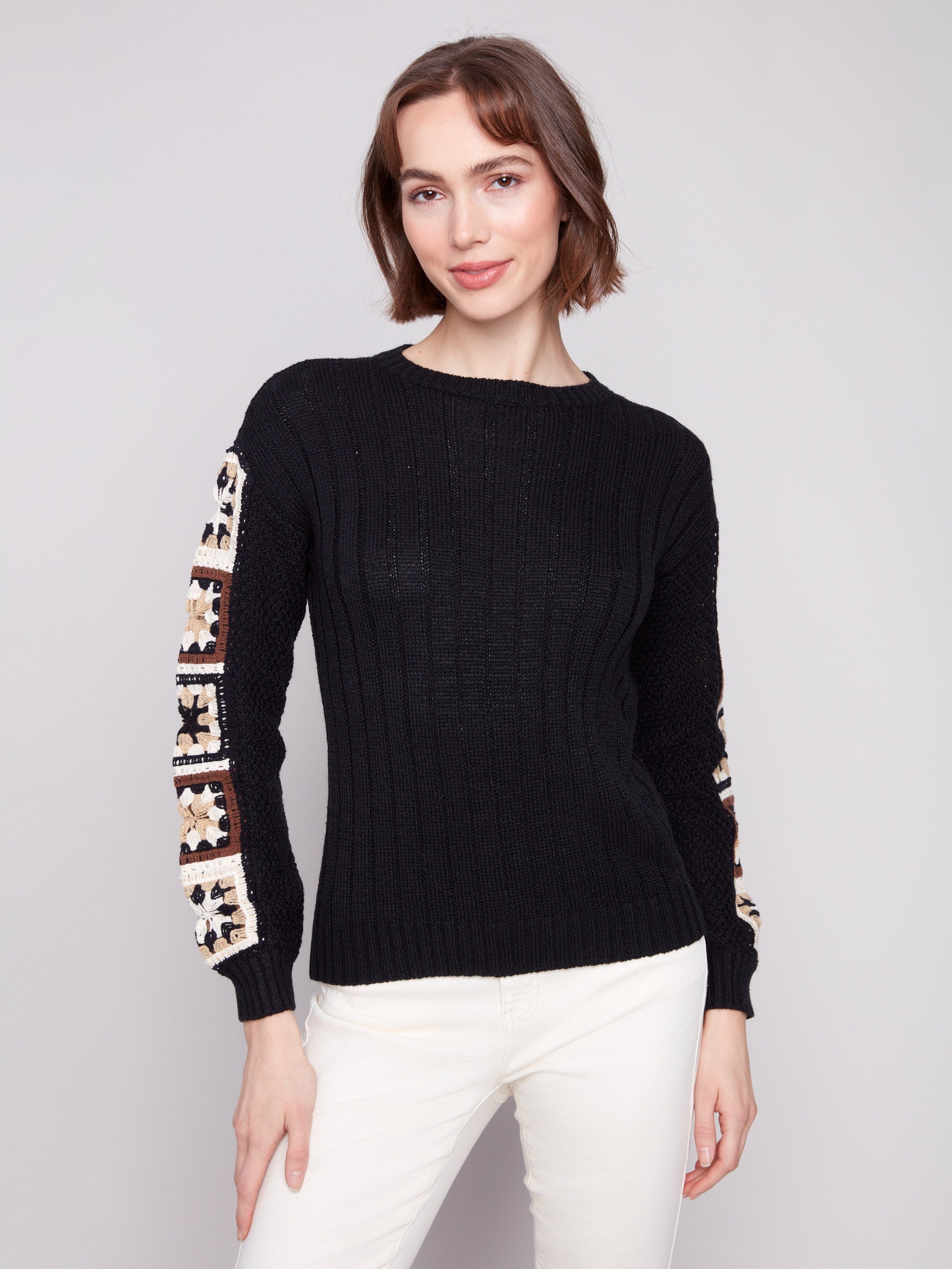 Elegant black sweater featuring intricate crochet sleeves, perfect for a stylish look by Charlie B.