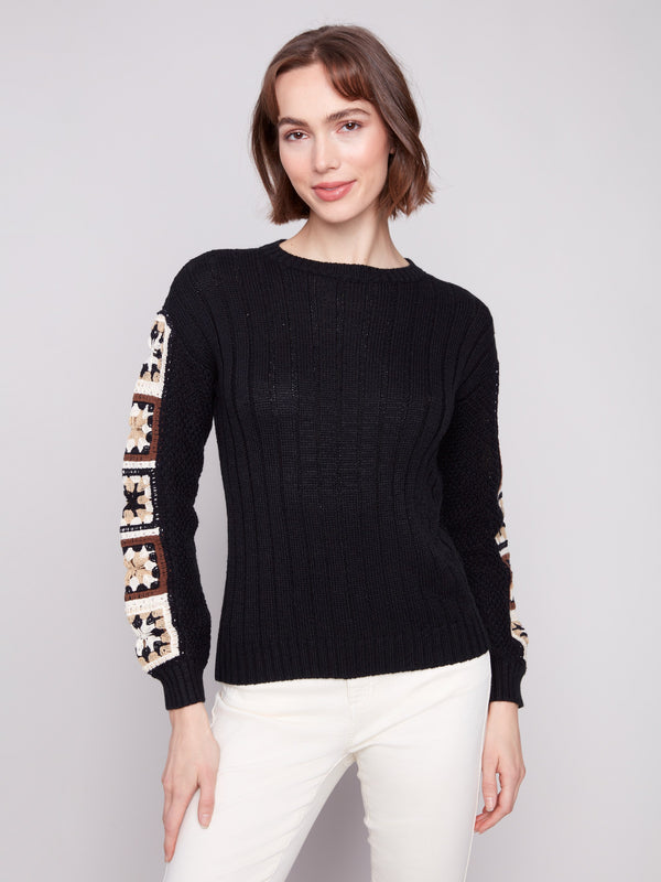 Elegant black sweater featuring intricate crochet sleeves, perfect for a stylish look by Charlie B.