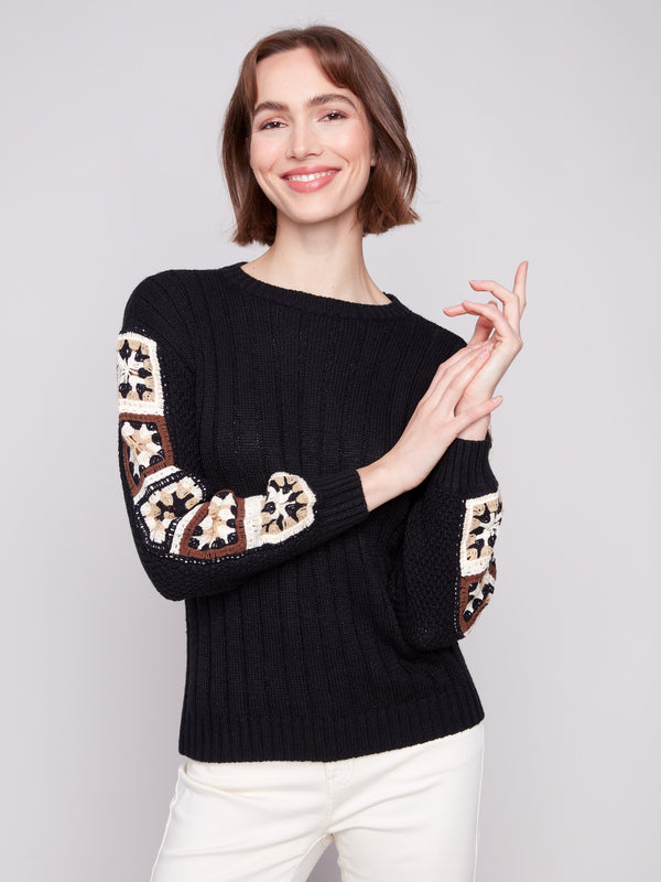 Stylish black sweater with distinctive crochet detailing on the sleeves, designed by Charlie B.