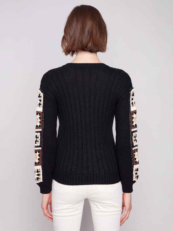 Classic black sweater showcasing beautiful crochet work on the sleeves for added flair by Charlie B.