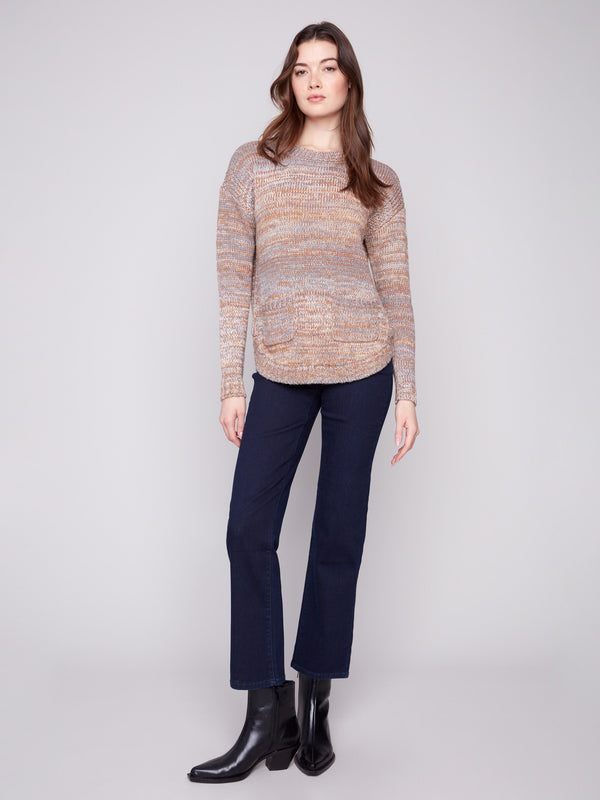 Full view of fog-colored sweater with front pockets and a round hem paired with dark jeans by Charlie B.