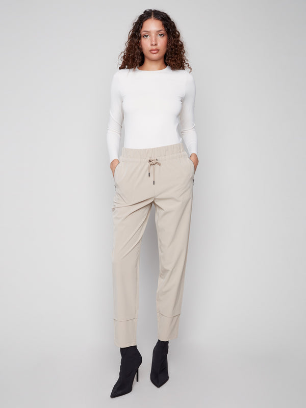 Greige slim-leg techno pants with a relaxed fit, featuring pull-on style and side zip pockets for convenience by Charlie B.