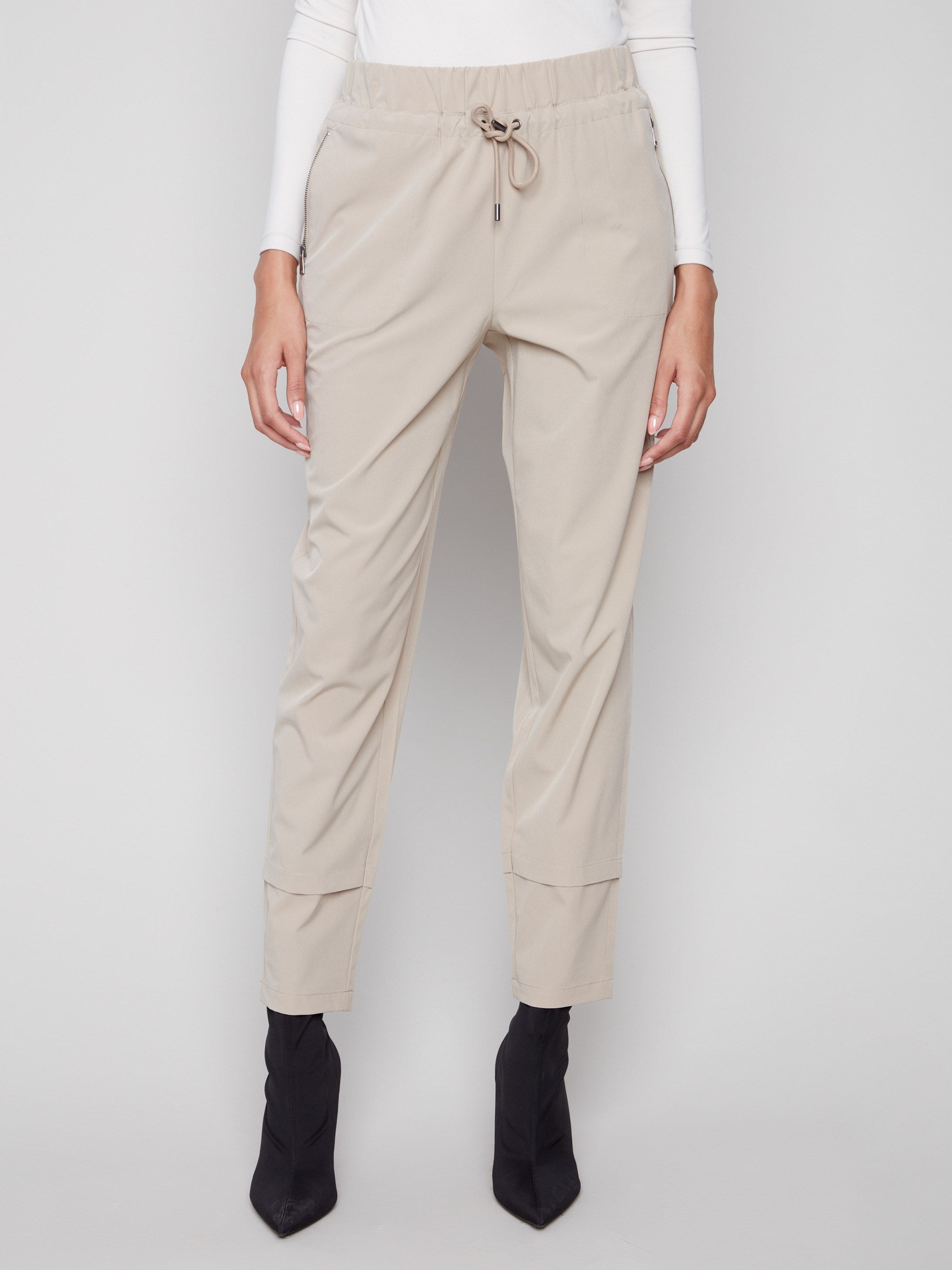 These greige techno pants offer a relaxed slim-leg fit with an elastic waistband and drawstring for added comfort by Charlie B.