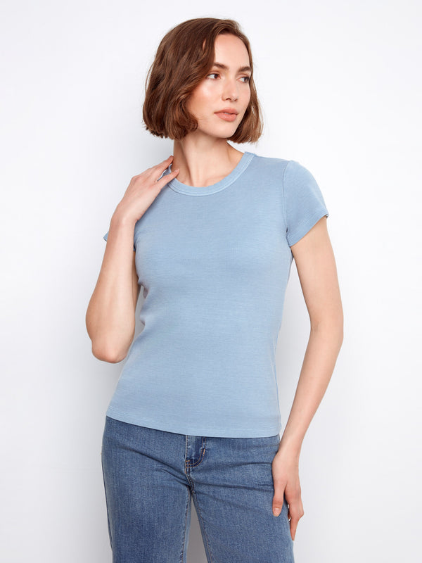 Blue top showcasing a flattering crew neck design, combining simplicity and elegance seamlessly in your outfits. By Charlie B.