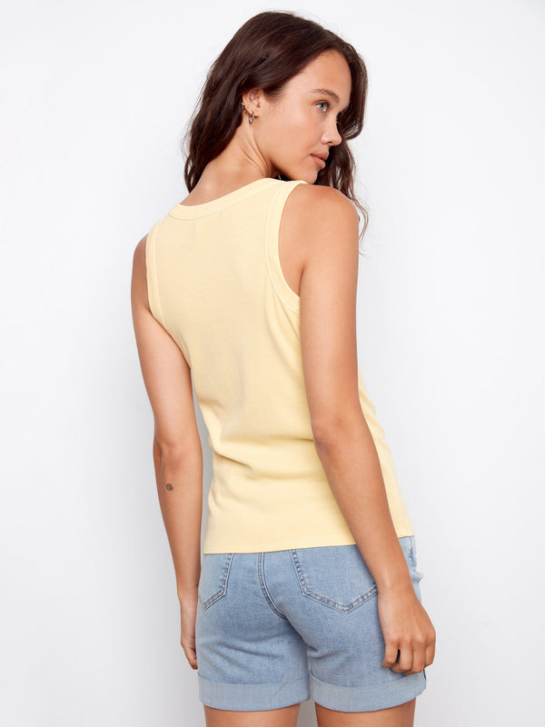 Chic yellow tank top in a soft fabric, complementing the rolled hem of the denim shorts effortlessly. Created by Charlie B.
