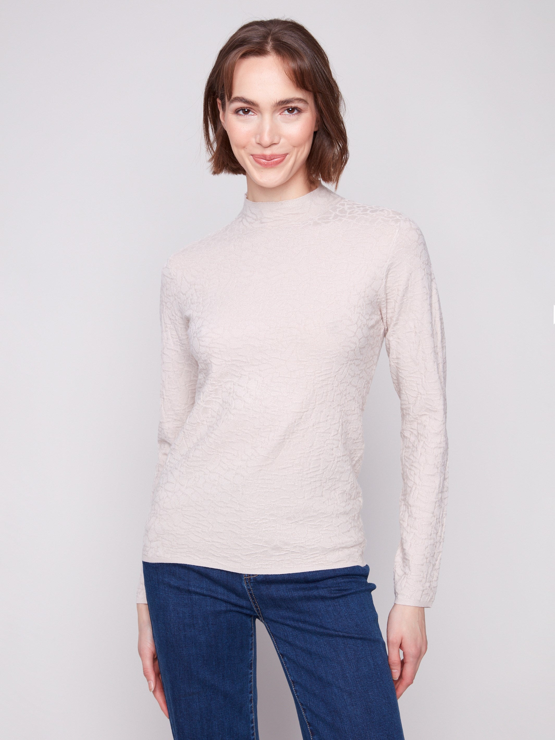 Oat sweater with a mock neck, paired with blue jeans, showcasing the slim fit design for a modern look by Charlie B.