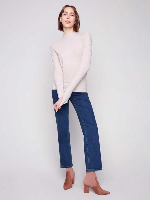 Mock neck oat sweater combined with blue jeans, offering a contemporary slim fit style by Charlie B.