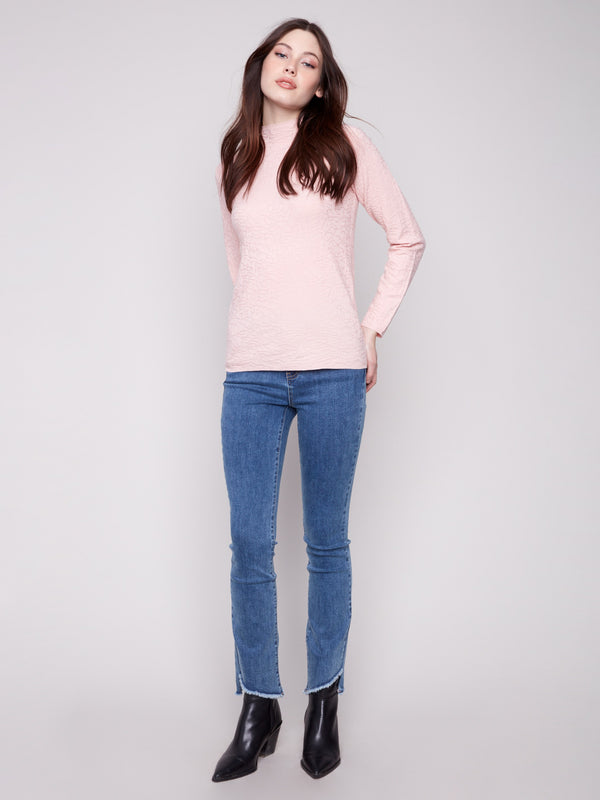 Textured ballet pink sweater paired with blue jeans, showcasing its elegant mock neck design by Charlie B.