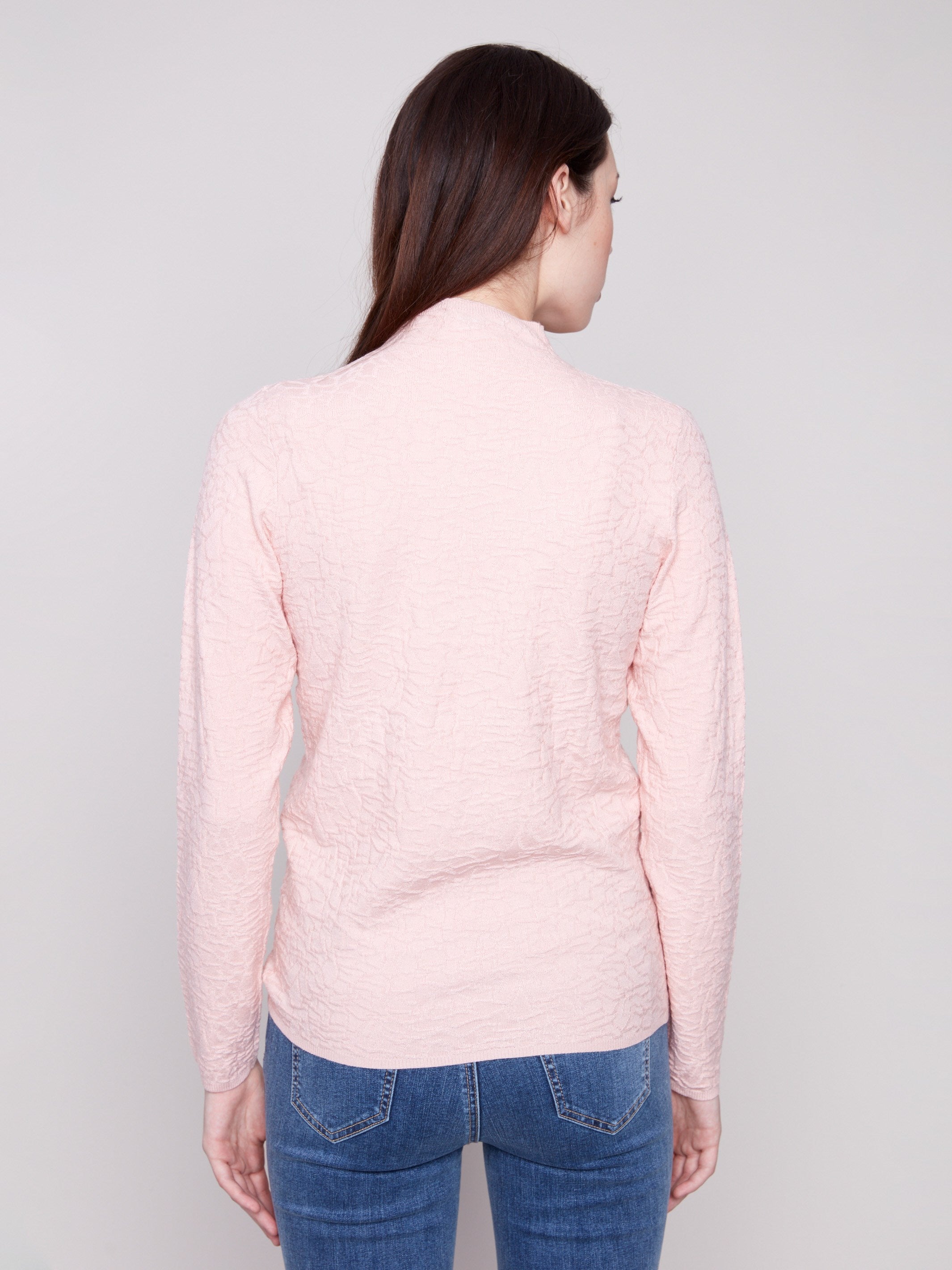 Long-sleeve ballet pink sweater styled with blue jeans, emphasizing the textured fabric by Charlie B.