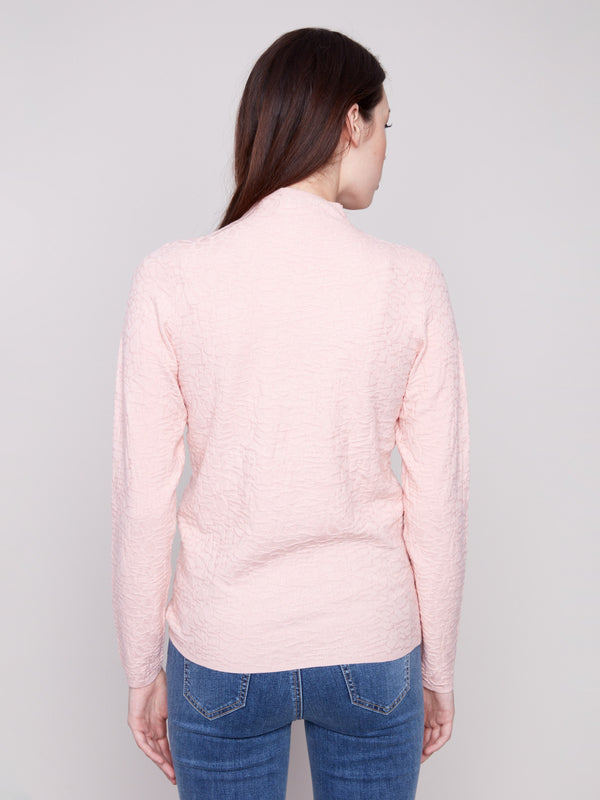 Long-sleeve ballet pink sweater styled with blue jeans, emphasizing the textured fabric by Charlie B.