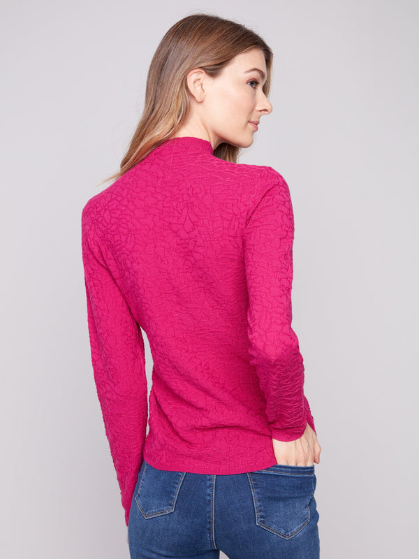 Chic hibiscus long-sleeve sweater showcasing its mock neck style, matched with blue jeans by Charlie B.