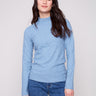 Oxford blue sweater featuring a mock neck paired with classic blue jeans, showcasing its elegant design by Charlie B.