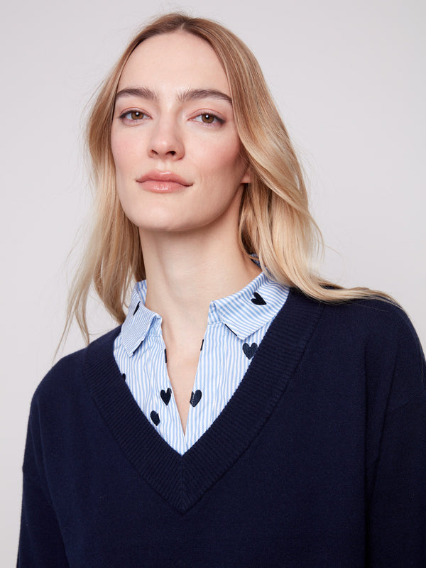 Elegant navy sweater showcasing a layered look with frayed finish at cuffs and hem, complemented by embroidered hearts by Charlie B.