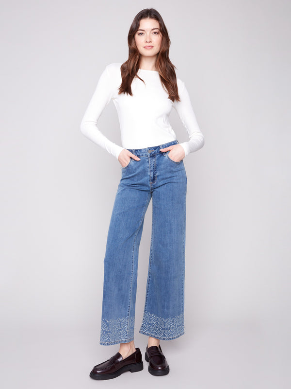Medium blue jeans featuring a wide leg design with elegant patterned studs, crafted from stretch denim material by Charlie B.