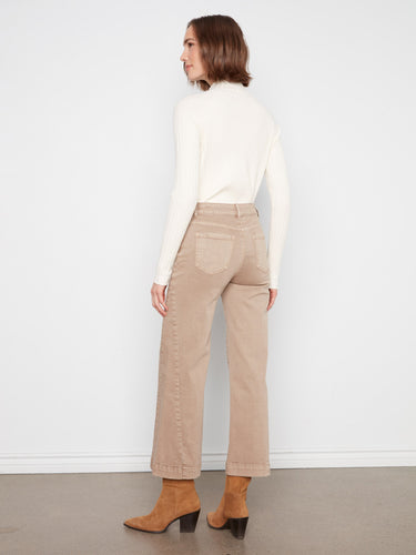 Latte-colored pants featuring five-pocket design, worn with a white top and brown boots for an elegant look by Charlie B.